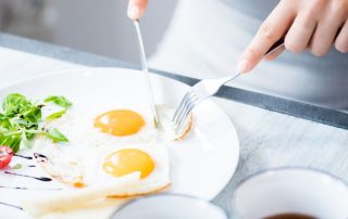 mujer comiendo huevos fritos fuente de proteína